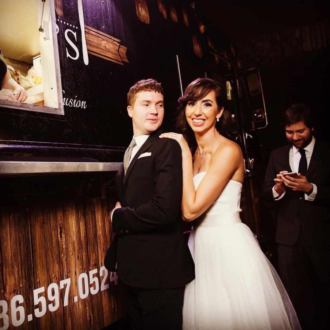 A couple celebrating in front of the Latin Fixin's food truck at their wedding